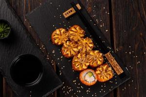 California sushi roll with crab, avocado and tobiko caviar served on black board top view close-up - Japanese asian food photo