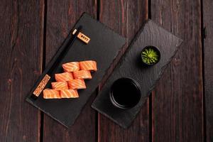 Sushi roll philadelphia with salmon and cucumber and cream cheese on black background. Sushi menu. Japanese food concept top view photo