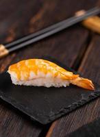 Japanese seafood sushi nigiri with shrimp on black and wooden background - asian cuisine concept photo