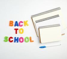 inscription back to school from multi-colored plastic letters and a stack of notebooks photo