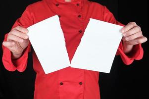 man in a red uniform holds a white sheet of paper torn in half photo