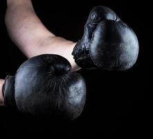 las manos de los hombres llevan guantes de boxeo negros de cuero viejos foto