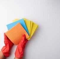 esponjas absorbentes cuadradas multicolores en sus manos con guantes de goma rojos foto