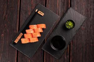 Sushi roll philadelphia with salmon and cucumber and cream cheese on black background. Sushi menu. Japanese food concept top view photo