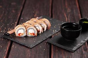 Sushi roll with smoked eel and tobiko with avocado and cheese close-up. Traditional delicious fresh sushi roll set. Sushi menu. Japanese cuisine restaurant. Asian food photo