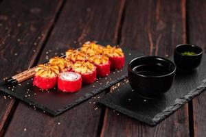 California sushi roll with crab and tobiko caviar served on black board close-up - Japanese food photo