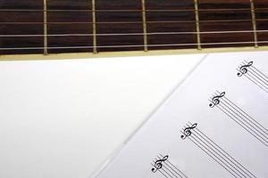 Focus the acoustic guitar neck and blur musical notes on white background. Love, music and learning concept. photo