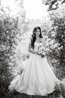 joven novia con un vestido blanco en un bosque de primavera en arbustos de lilas foto