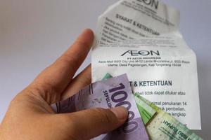 Jakarta, Indonesia in December 2022. Isolated white photo of a hand holding a shopping receipt after shopping at AEON Mall