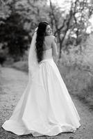 una joven novia con un vestido blanco está girando en un camino foto