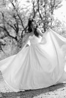 a young girl bride in a white dress is spinning on a path photo