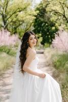 a young girl bride in a white dress is spinning on a path photo