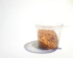 This is a plastic container in the shape of a small, transparent tube filled with crumbs of biscuits. photo