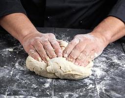 baker kneads white wheat flour dough photo