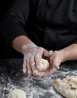 cook making dough balls on a black wooden table photo