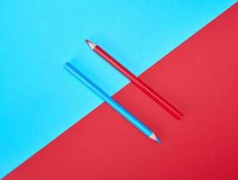 red and blue wooden pencils on color abstract background photo