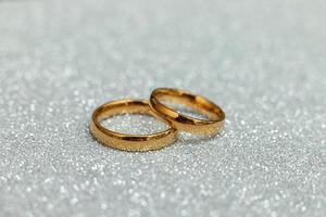 Te casarías conmigo. dos anillos de boda dorados sobre fondo plateado brillante. concepto de boda de propuesta de matrimonio de compromiso. S t. postal del día de san valentín. pancarta en el día de san valentín. copie el espacio foto