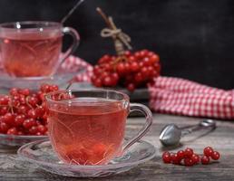 hot viburnum tea in a transparent cup with a handle and saucer photo