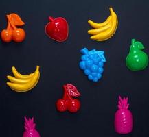 multicolored plastic toys fruits on a black background photo