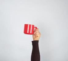 red ceramic cup in a female hand on a white background photo