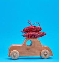 pequeño coche de madera para niños lleva un corazón rojo de mimbre foto