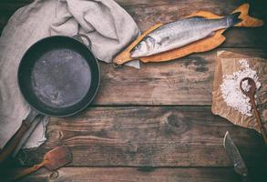 fresh whole sea bass fish on brown cutting board photo