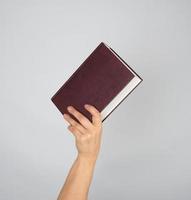 hand holds a closed book in hardcover photo