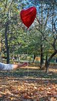 mano femenina sosteniendo un globo rojo en forma de corazón foto