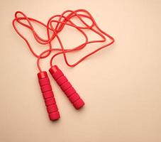 red sports rope for jumping and cardio load on a beige background photo