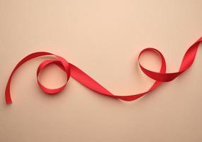 red silk ribbon twisted on a beige background, festive backdrop photo