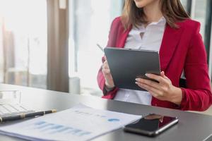 marketing, finanzas, contabilidad, planificación, el presidente de la empresa se sienta en su oficina con una tableta, calculadora, bolígrafo y papel cuadriculado pegado a una pizarra para su trabajo. foto