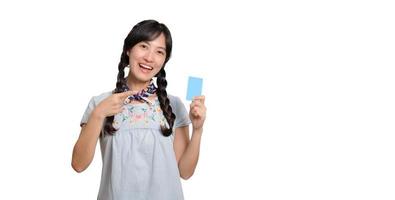 Portrait of beautiful happy young asian woman in denim dress holding credit card on white background photo