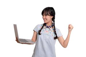 retrato de una hermosa y feliz joven mujer asiática independiente vestida de mezclilla usando un trabajo portátil con éxito en el fondo blanco foto