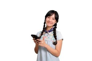 retrato de una feliz y hermosa joven asiática vestida de mezclilla usando un smartphone con fondo blanco. foto de estudio