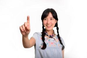 retrato de una hermosa joven asiática feliz vestida de denim tocando una pantalla invisible de fondo blanco. foto
