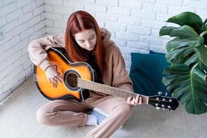 mujer joven, tocar la guitarra, en casa foto