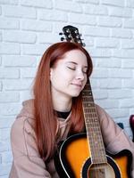 Young woman playing guitar at home photo