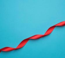 curled red satin ribbon on blue background photo
