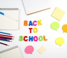 inscription back to school from multi-colored plastic letters and a stack of notebooks photo