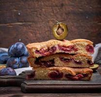 stack of triangular slices of sponge cake with blue plums photo