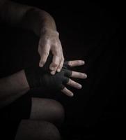 man wraps his hands in black textile bandage for sports photo