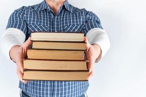man in blue plaid shirt holding a stack of books photo