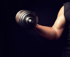 hand of a man with big biceps holds a steel type-setting dumbbell photo