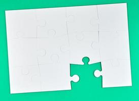 game of puzzles made of white paper pieces interconnected on a green background photo