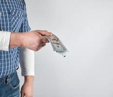 man in a blue plaid shirt and jeans holds a stack of American paper money photo