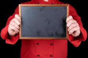 chef con uniforme rojo sosteniendo un marco de madera vacío foto
