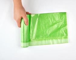 female hand unwind green roll with plastic bags for garbage photo