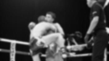 Blurred images black and white photo style of Thai boxing or Muay Thai or Kickboxing which local and foriegn boxer are fighting on the ring at indoor stage as martial art sport. Muay Thai Kick boxing