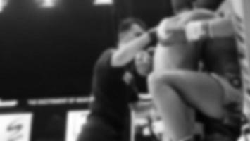 Blurred images black and white photo style of Thai boxing or Muay Thai or Kickboxing which local and foriegn boxer are fighting on the ring at indoor stage as martial art sport. Muay Thai Kick boxing
