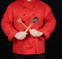 chef en uniforme rojo con cucharas de madera viejas foto